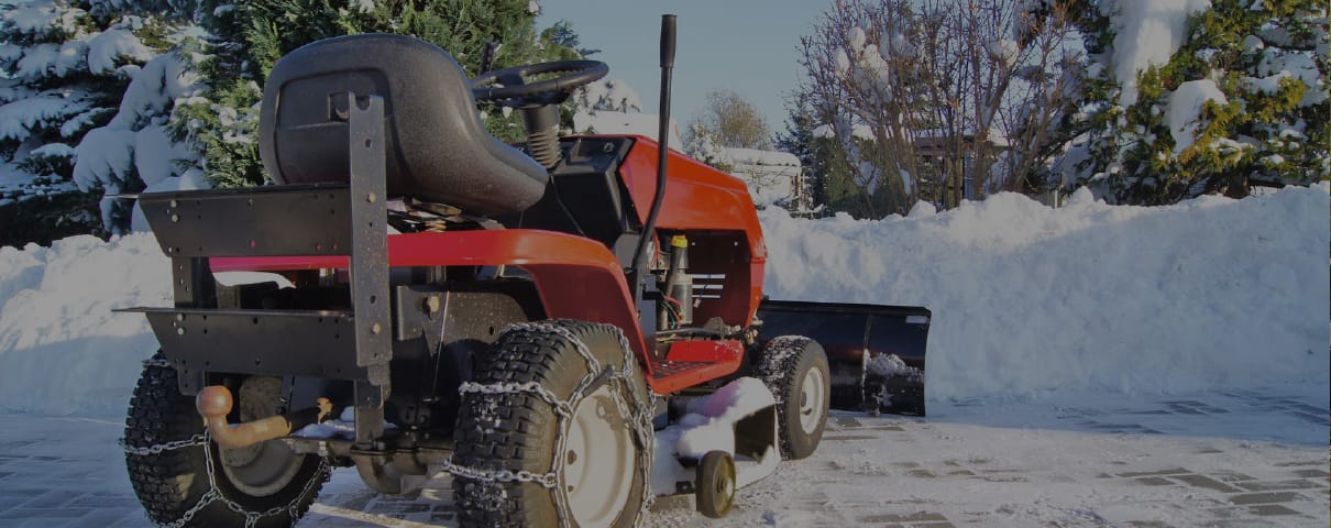 Räumfahrzeug mit Schneeschild auf einer frisch geräumten Hoffläche